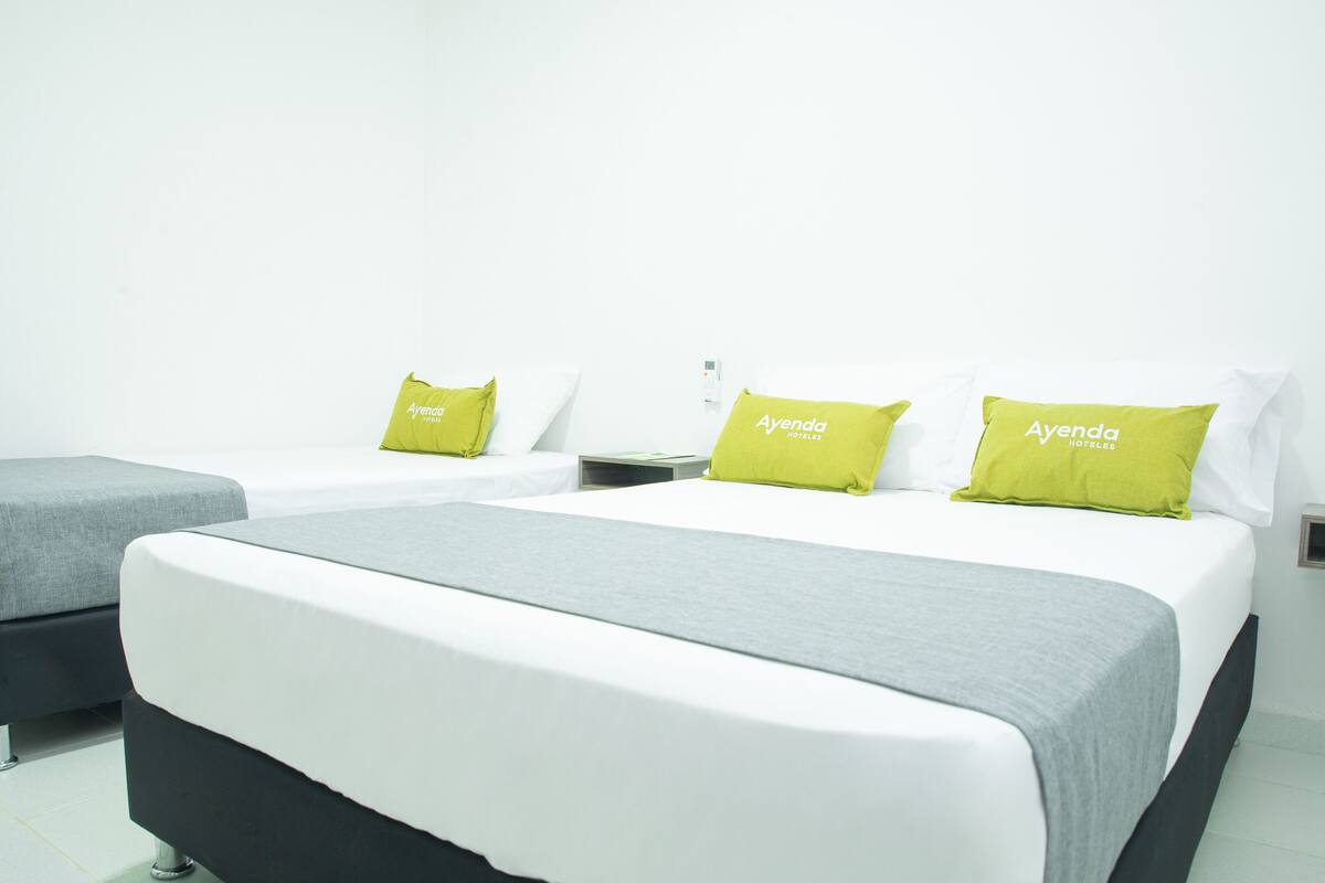 Habitación de hotel con una cama grande, dos mesitas de noche y dos sillas.
