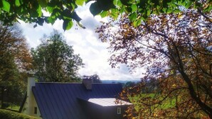 Une maison avec un toit en pente, entourée d’arbres et de verdure.