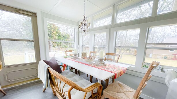 A dining area with a white table, wicker chairs, and a chandelier. - A Cozy, quiet and most perfect cottage beautifully located on a waterfront cove. (BURNET)
