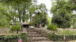 A stone staircase leading up to a gazebo with an American flag, surrounded by greenery and a body of water reflecting the scene. - A Cozy, quiet and most perfect cottage beautifully located on a waterfront cove. (BURNET)