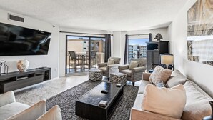 A modern living room with a flat-screen TV, comfortable seating, a fireplace, and a balcony with a city view. - Inlet Reef 518-Beachfront Complex without Beachfront Prices! (Destin)