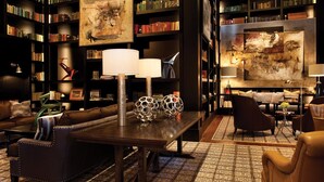 A cozy library with leather sofas, a wooden coffee table, and bookshelves filled with books.