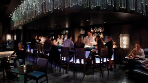 A bar area with a curved seating arrangement, a bartender, and a well-stocked bar counter.