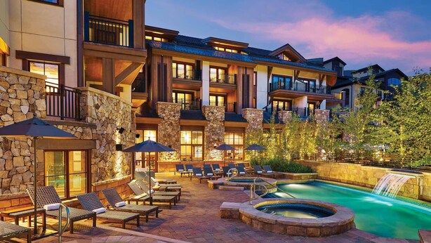 A hotel with a pool, outdoor seating, and a waterfall.