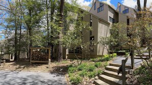 A multi-story building with a wooden deck and steps leading to the entrance. - Eagles Court Ski In/Ski Out Condo with Walkable Location & Mountain Views! (Wintergreen Resort)