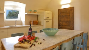 Una cucina con un piano di lavoro in marmo, una ciotola blu grande e una bottiglia d'olio d'oliva.