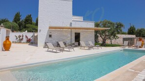 Una villa moderna con piscina, area relax all'aperto e facciata bianca.