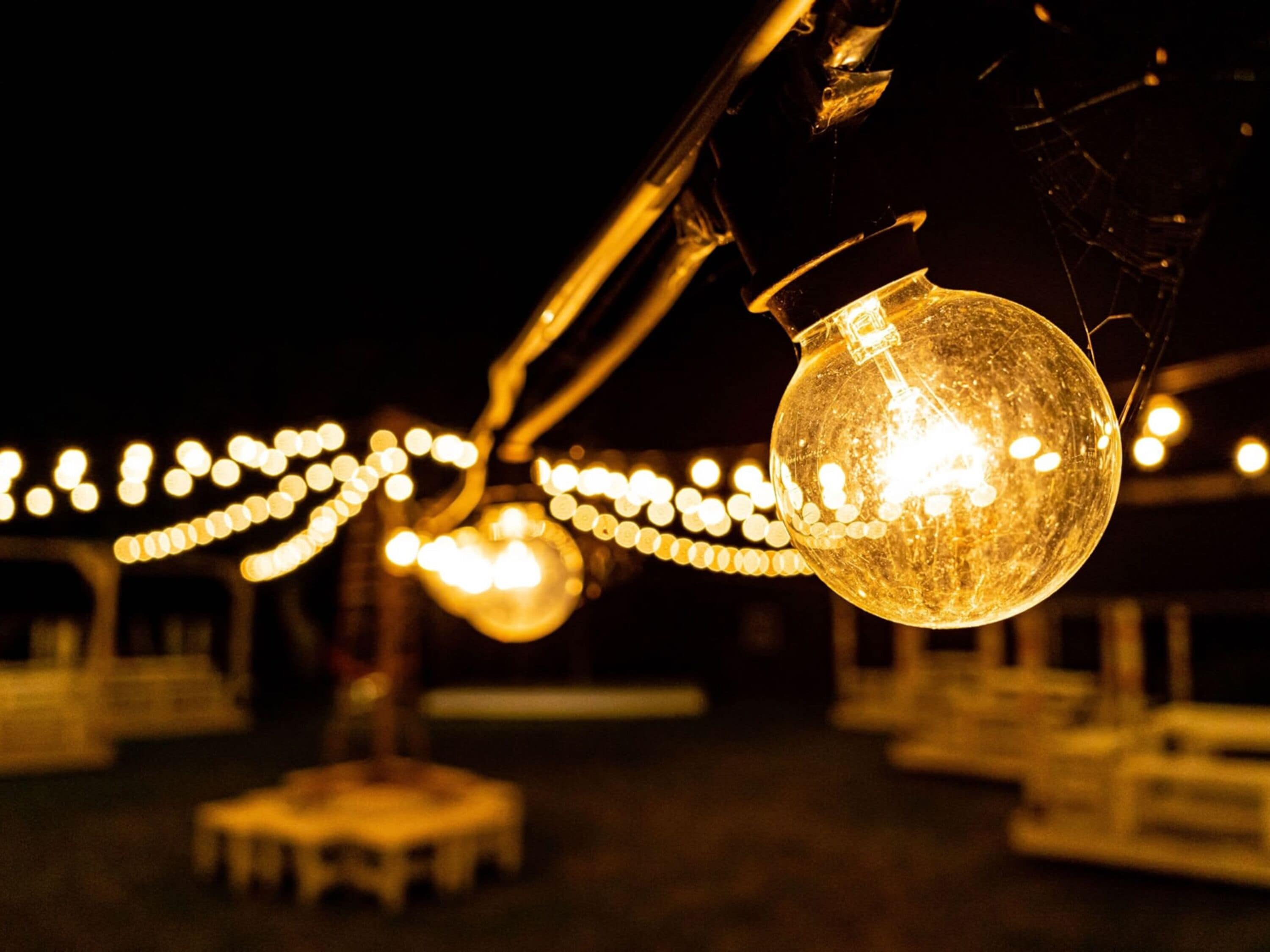 A close-up of a spherical light fixture with a clear glass cover, hanging from a metal structure.