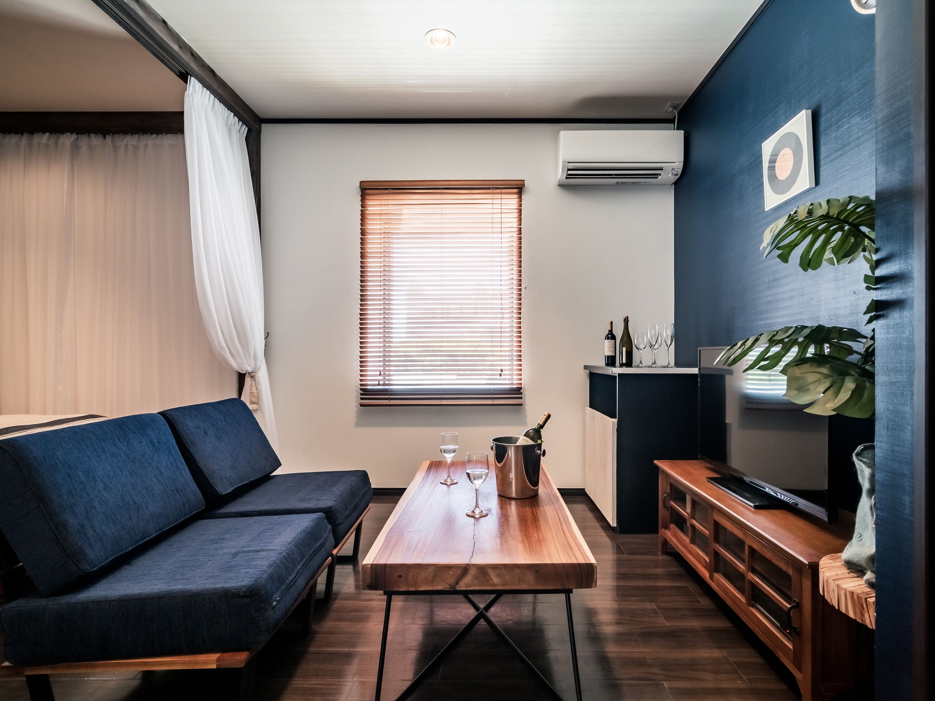 Una sala de estar moderna con un sofá, una mesa de centro de madera, un televisor y una planta.