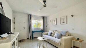 A modern living room with a sofa, a coffee table, a TV, and a ceiling fan.