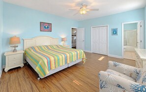 A bedroom with a bed, nightstands, a ceiling fan, and a door leading to a bathroom.