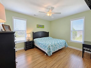 A bedroom with a bed, a nightstand, a dresser, and a ceiling fan. - Billy-Lisa - Second Row in Garden City Beach, SC (Garden City)