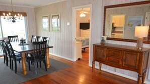 A dining area with a wooden table and chairs, a chandelier, and a wooden cabinet with drawers. - Swamp Fox (Formerly Footprints) - Second Row in Garden City Beach, SC (Garden City)