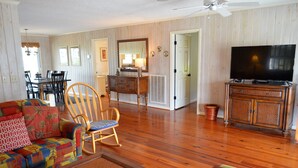 A living room with a sofa, chairs, a television, and a dining area with a table and chairs. - Swamp Fox (Formerly Footprints) - Second Row in Garden City Beach, SC (Garden City)