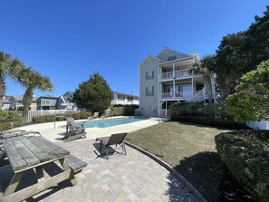 A residential building with a pool, patio furniture, and a well-maintained lawn.