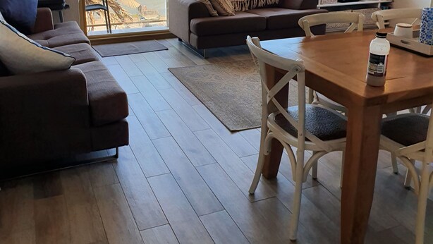 Un salón con un ventanal grande con vistas a una playa, un sofá, una mesa de centro y un televisor.