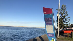 Un cartel con información direccional y normas para una zona costera.