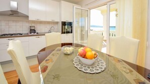 A modern kitchen with white cabinets, a gas stove, and a view of the sea through a glass door. - Vacation home Ana by Interhome (Maslenica)