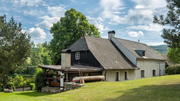 Kaksikerroksinen talo, jossa on kalteva katto, savupiippu ja katettu kuisti.