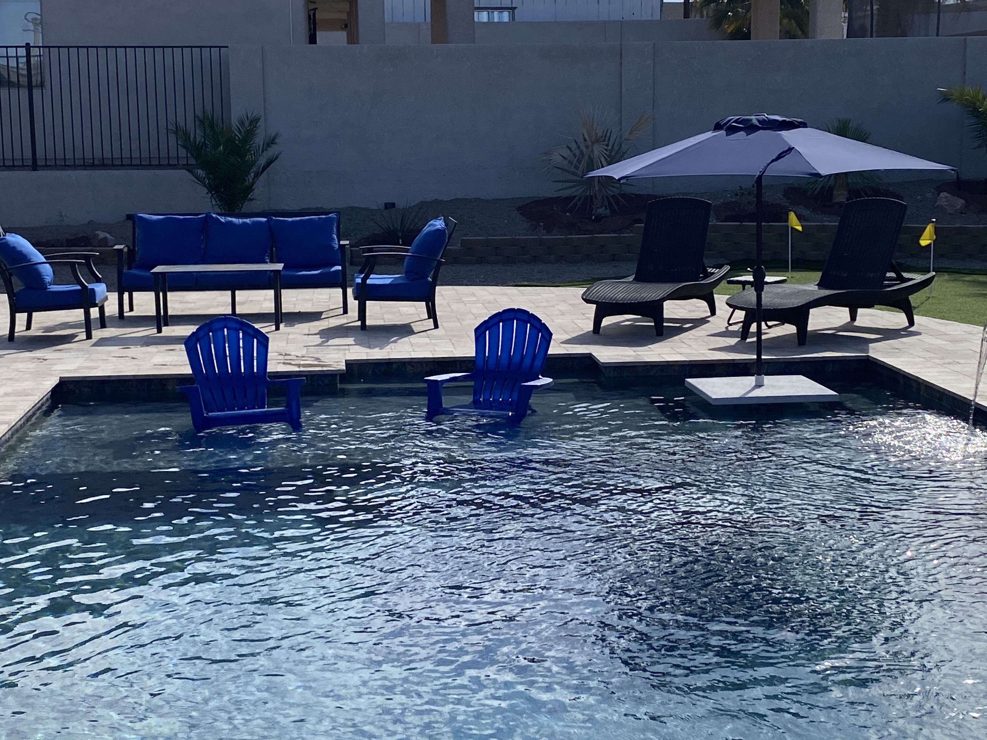 Ein Swimmingpool mit blauen Liegestühlen und einem Sonnenschirm.