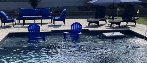 Ein Swimmingpool mit blauen Liegestühlen und einem Sonnenschirm.