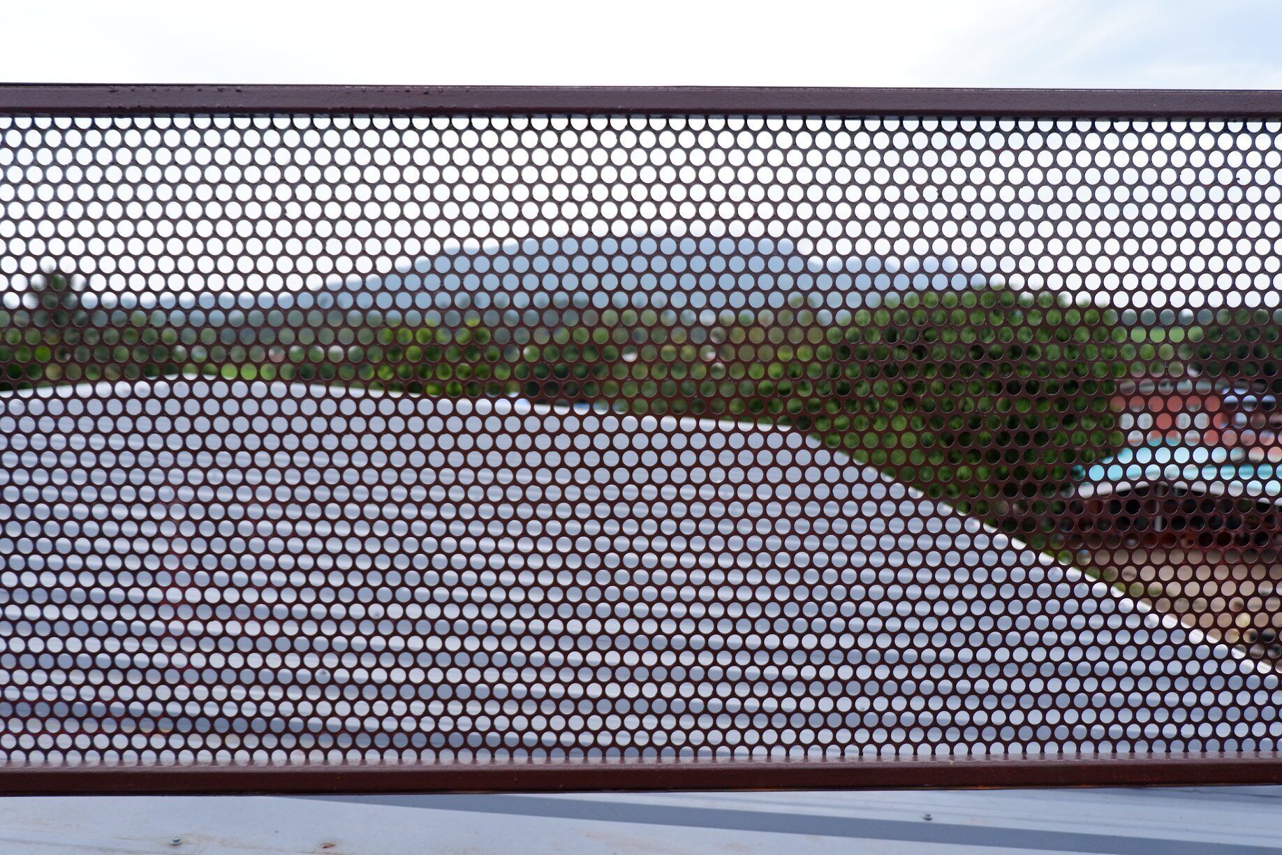 A metal fence with a grid pattern, likely a security barrier.