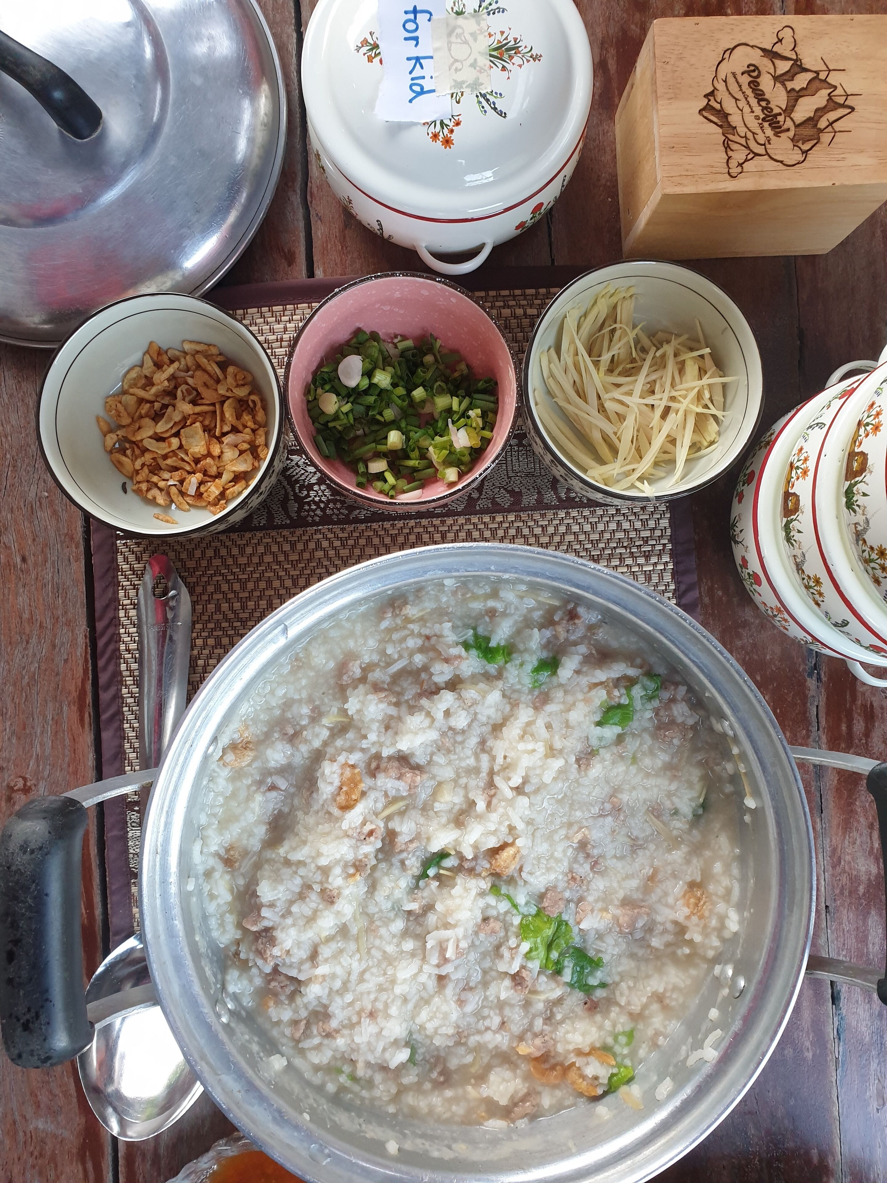 A table with various food items including a pot of rice, bowls of vegetables, and a box labeled "Peach".