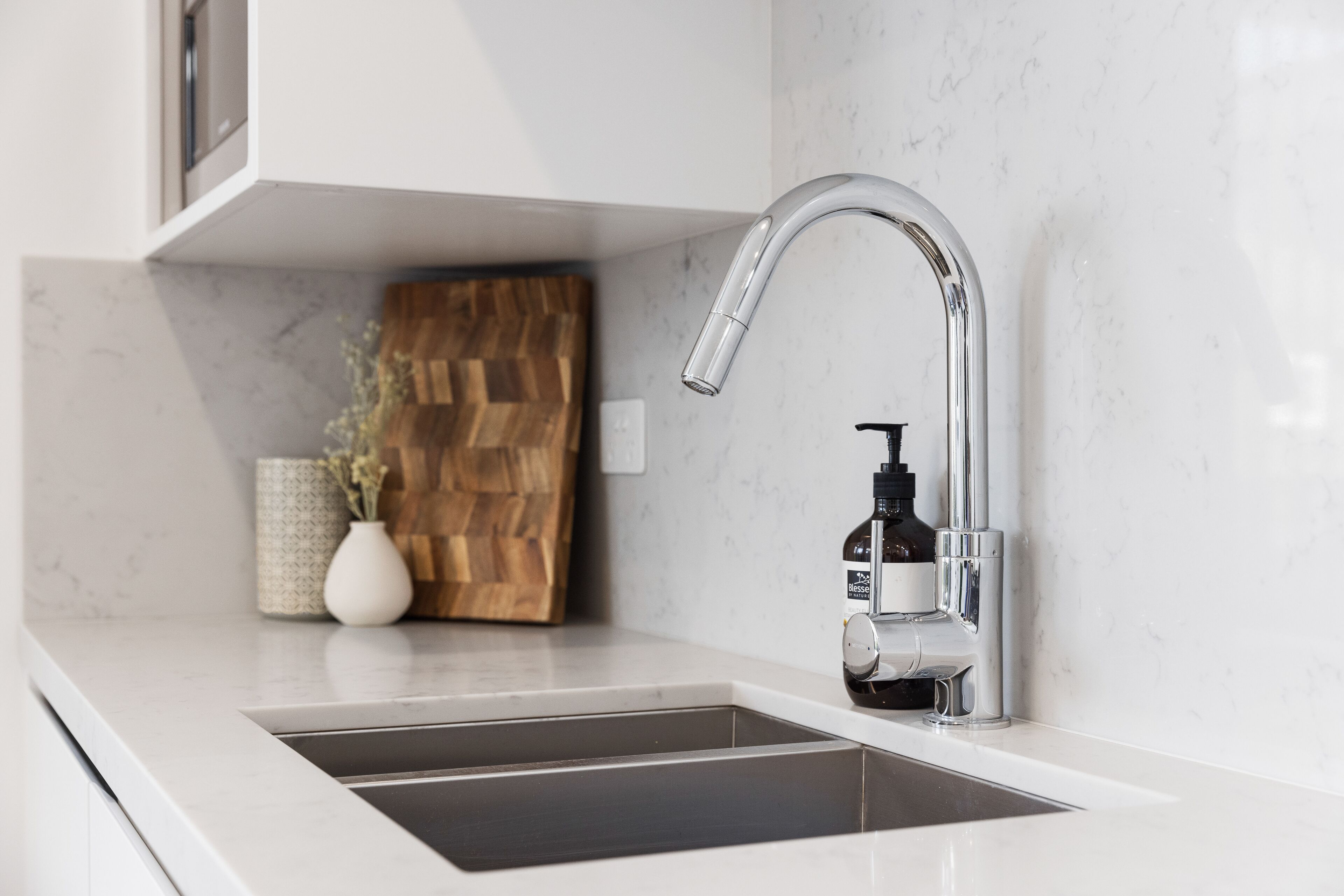 A modern kitchen with a sleek stainless steel faucet, a built-in sink, and a wooden accent wall.
