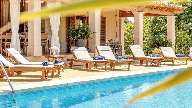 Ein Poolbereich mit Liegestühlen, einer Pergola und einem Topfpflanzen.