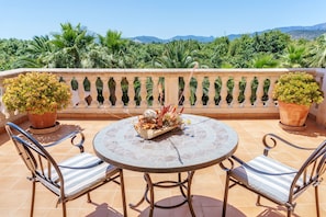 Una mesa redonda con dos sillas, un centro de mesa decorativo y vistas de exuberante follaje y montañas.