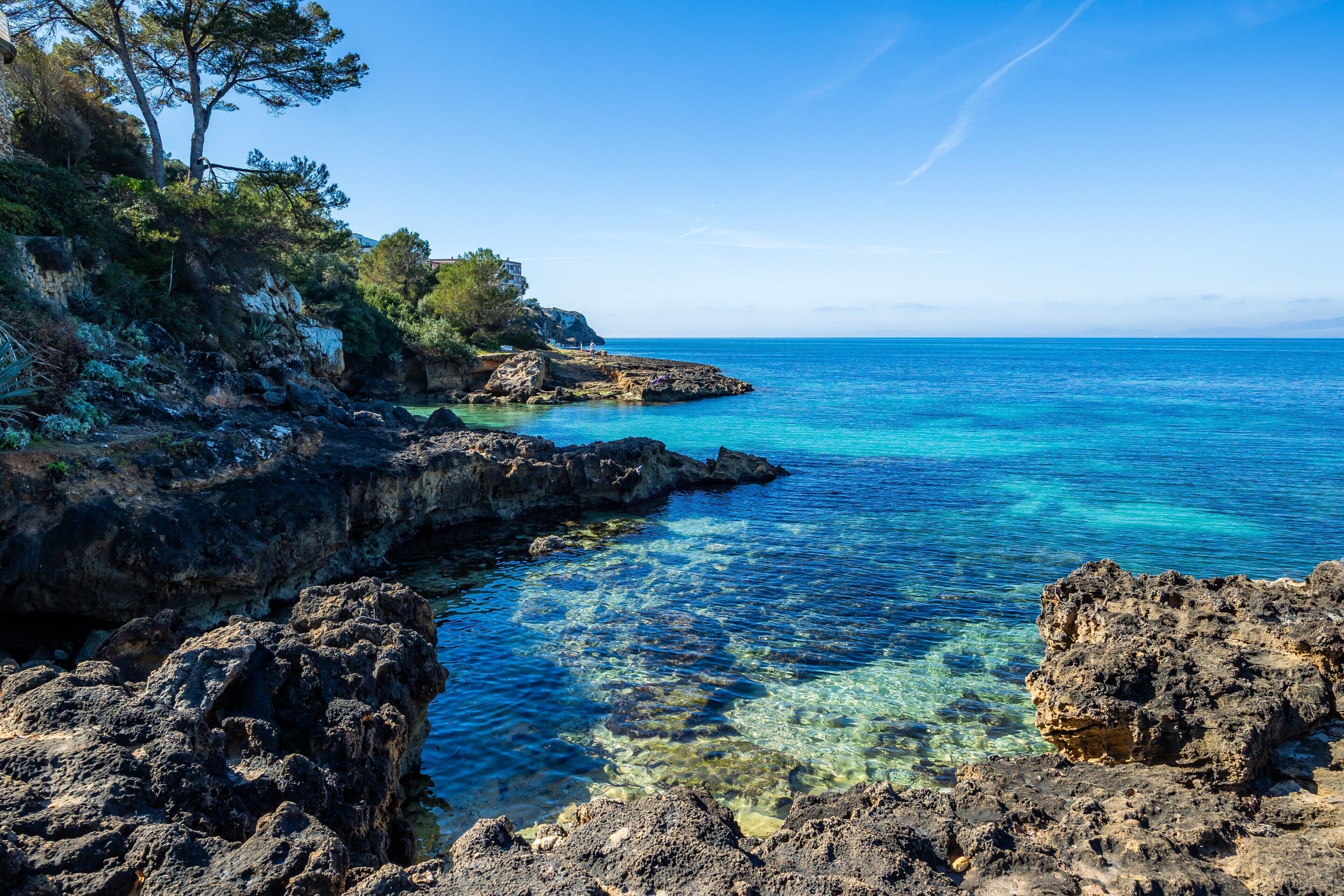 Un paysage côtier caractérisé par un terrain rocheux et une eau d’un bleu limpide.