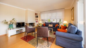 A living room with a TV, sofa, chairs, and a fireplace. - Peaceful Seafront Location – Casa Es Pí (Llucmajor)