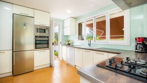 A modern kitchen with a refrigerator, oven, microwave, dishwasher, and a gas stove. - Peaceful Seafront Location – Casa Es Pí (Llucmajor)