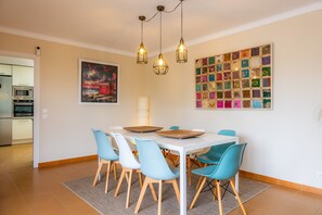 Ein Essbereich mit einem weißen Tisch, blauen Stühlen und einem Wanddekor.