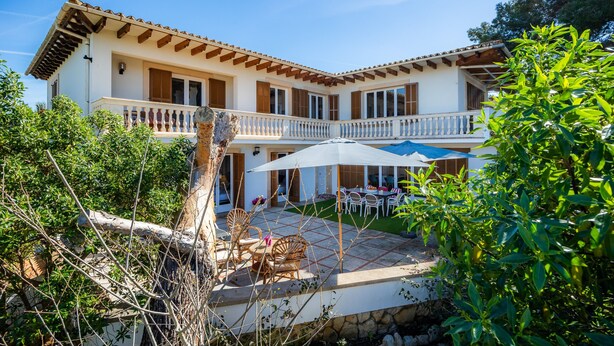 A two-story building with a balcony, outdoor seating, and a stone wall. - Peaceful Seafront Location – Casa Es Pí (Llucmajor)