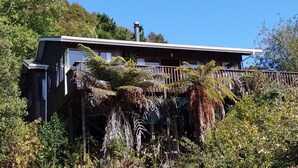 A wooden building with a balcony, surrounded by dense vegetation and trees.