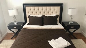 A neatly made bed with a dark brown quilt, two white pillows, and a folded white towel on the bed. There are two bedside tables with lamps and a dark wooden headboard. - Cozy Condo in Downtown Long Beach, 2 min walk to the Beach,parking place+garage  (Long Beach)