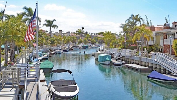 A marina with boats docked, a flagpole with an American flag, and palm trees. - Cozy Condo in Downtown Long Beach, 2 min walk to the Beach,parking place+garage  (Long Beach)