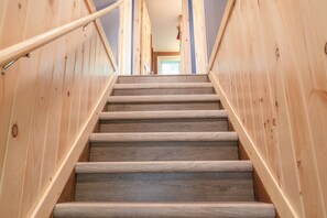A wooden staircase with a handrail, leading to a room with a door at the top.