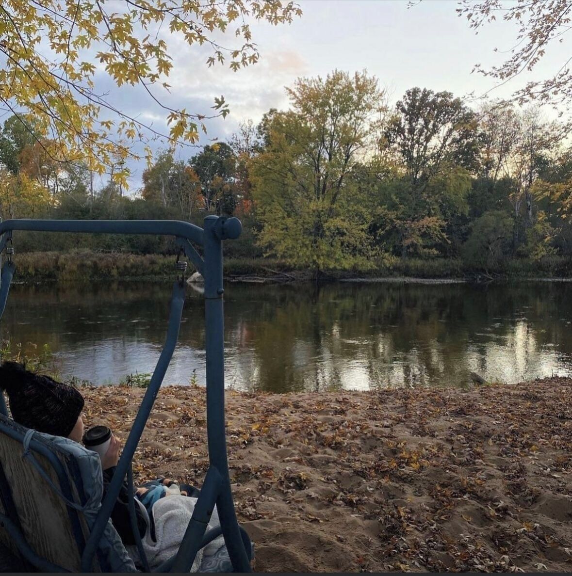 A lakeside view with a bench and a metal railing overlooking the water.