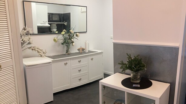 A modern bathroom with a white vanity, a mirror, and a small white cabinet with glass doors.