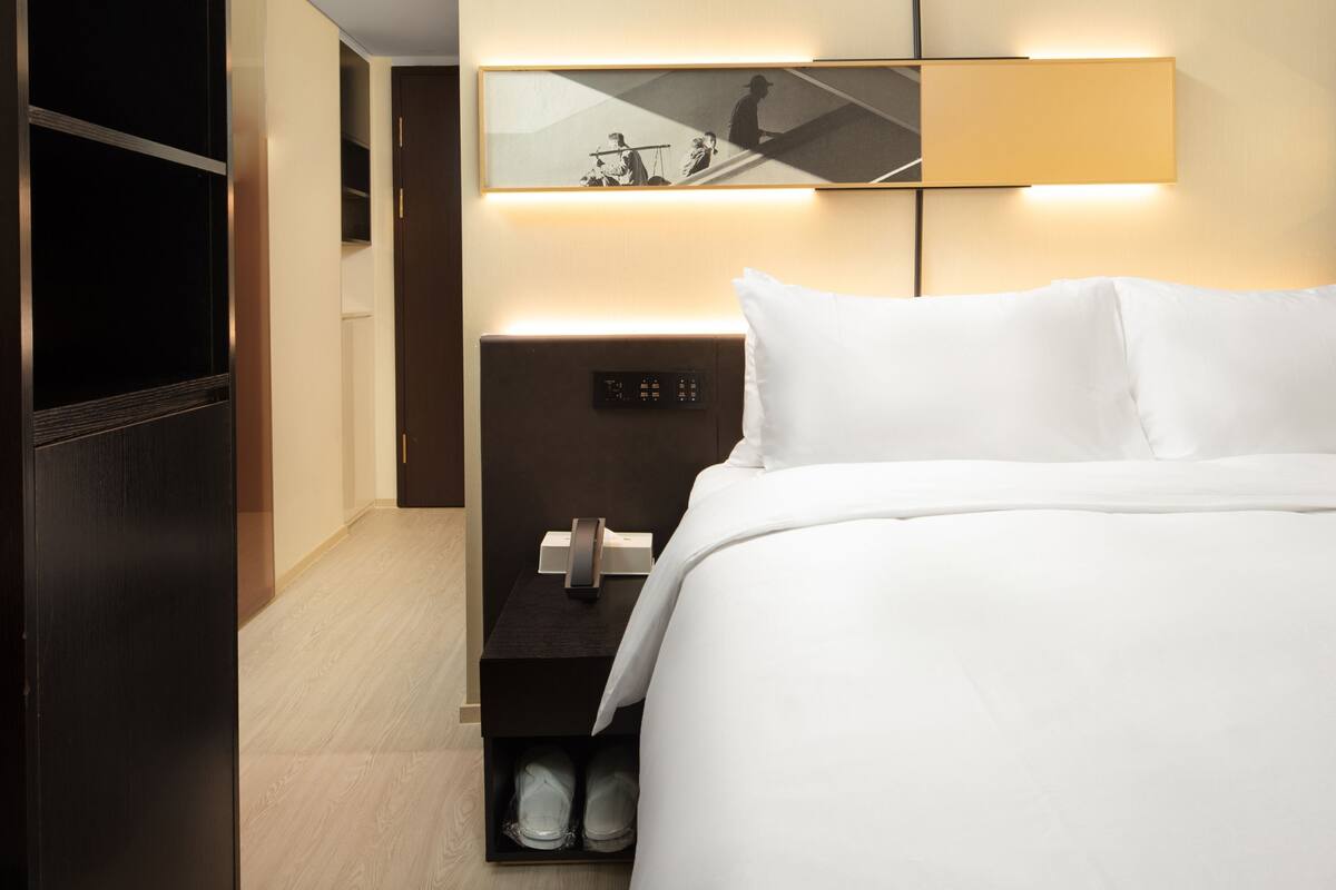 Ein Hotelzimmer mit Bett, Nachttisch, Spiegel und Kleiderschrank.
