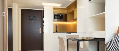 A modern hotel room with a dining area, a kitchen, and a living space.