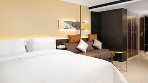 A modern hotel room with a large bed, a sofa, a small table, and a wall-mounted lamp. - CITIGO HOUSE Tianhe Guangzhou (Guangzhou)