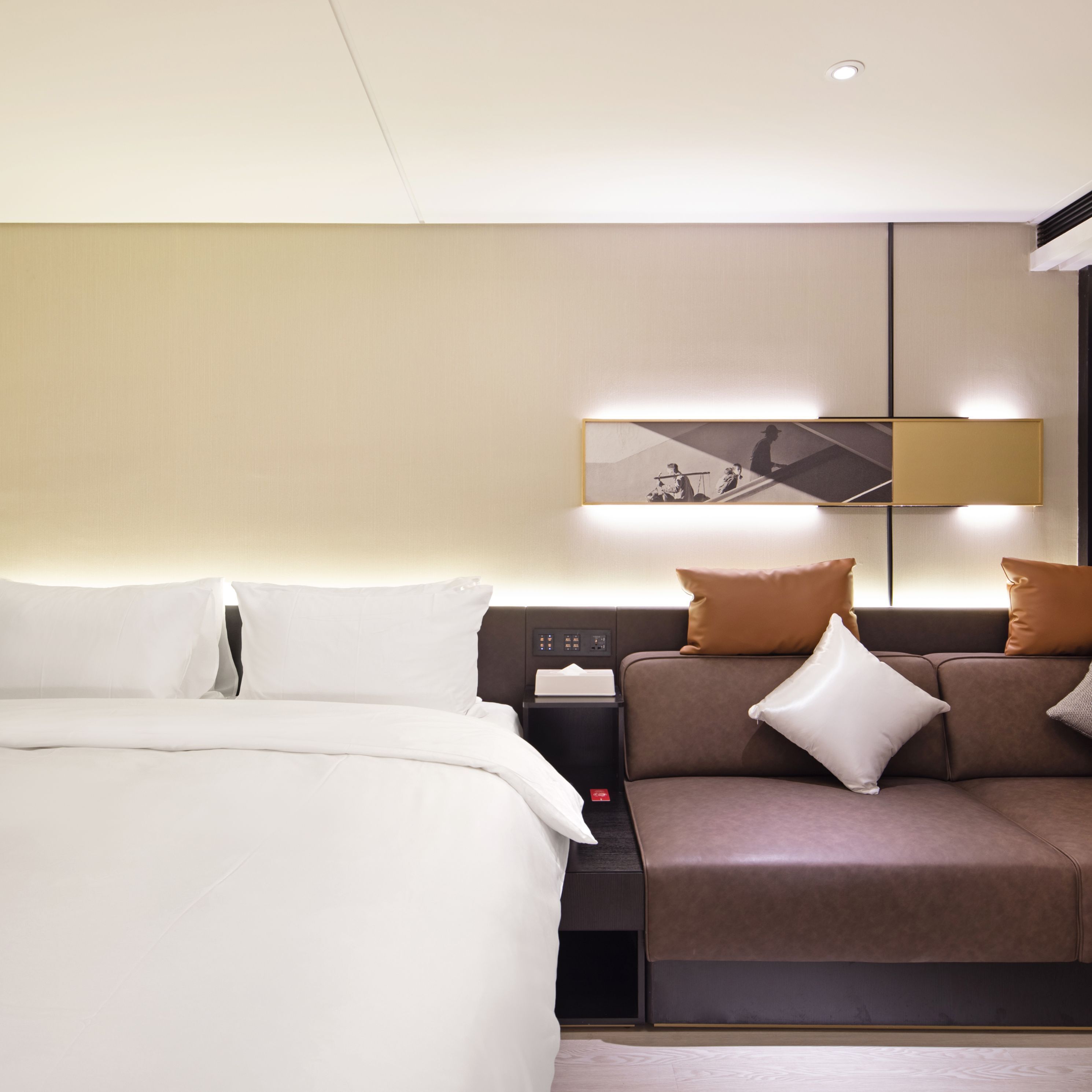 Una habitación de hotel moderna con una cama, un sofá y una mesita de noche.