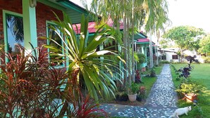 A pathway leading to a house with a tiled roof and a garden with various plants. - Swiss Chalet Garden Pool Resort (Krabi)
