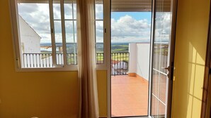 Habitación con vista a un balcón, una puerta corrediza de vidrio y una silla.