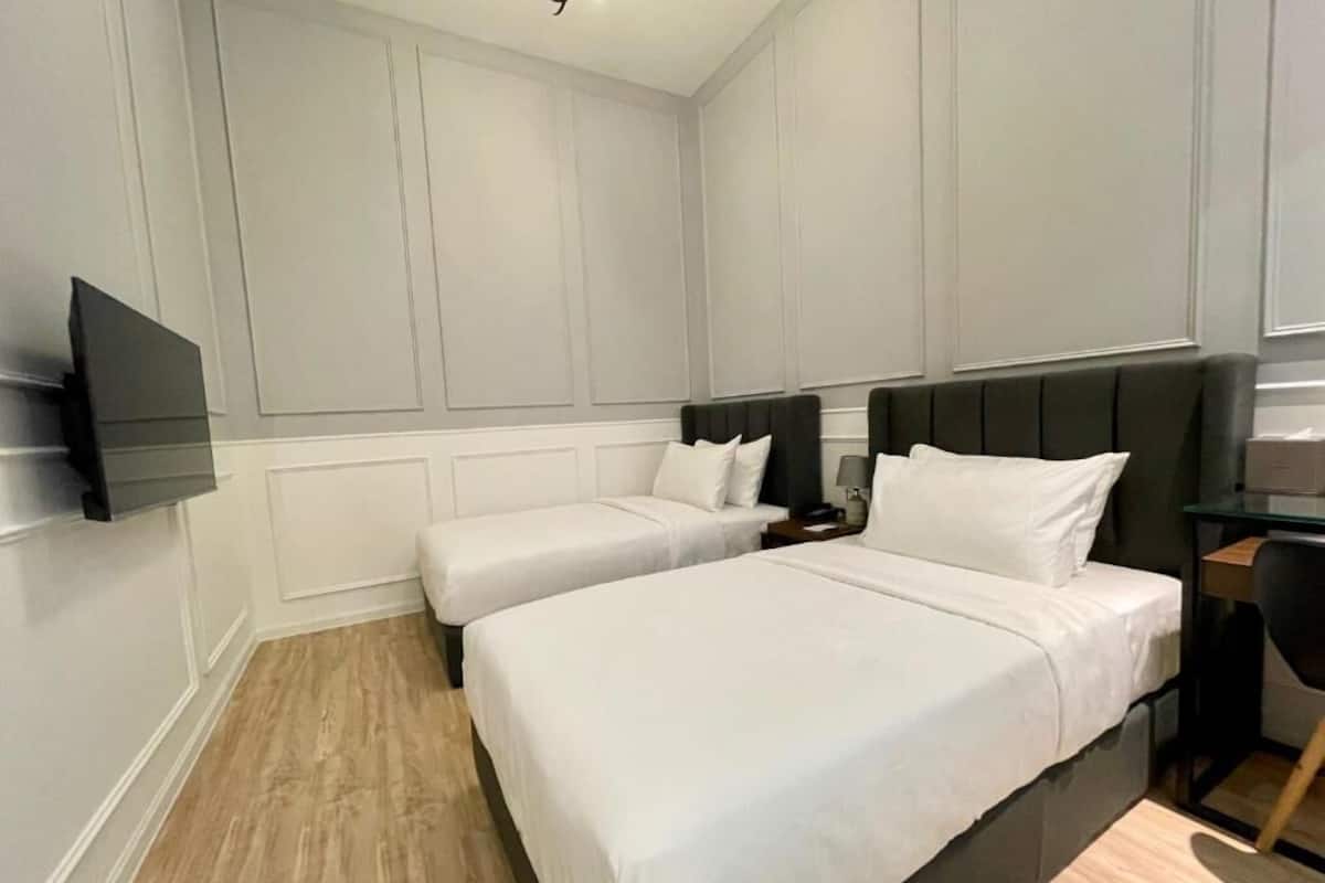 A hotel room with two beds, a flat-screen TV, a desk, and a chair.