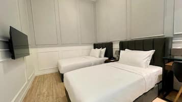 Habitación de hotel con dos camas, un televisor de pantalla plana, un escritorio y una silla.