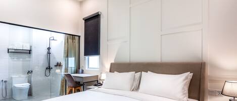 Una habitación de hotel moderna con una cama grande, un escritorio y una zona de ducha.